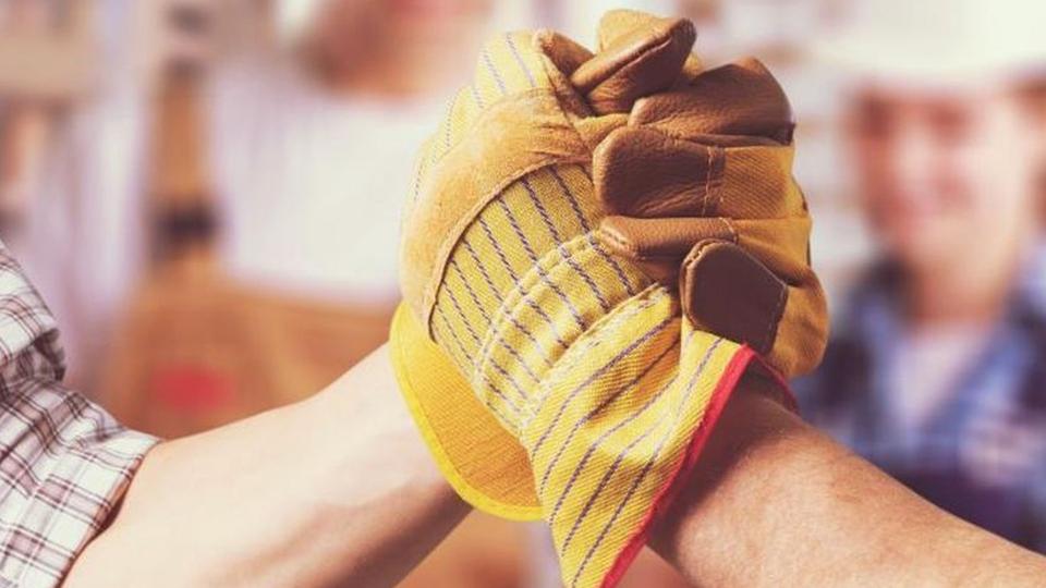 Handschlag von zwei Handwerkerinnen oder Handwerkern auf einer Baustelle